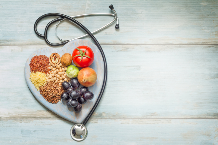fresh produce and grains surrounded by stethoscope in shape of heart