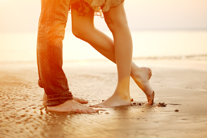 Photo showing legs of couple standing very close on shore facing each other