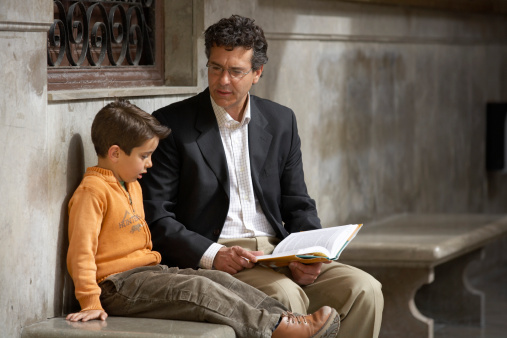 Man and young boy sit together to read book