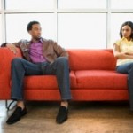 African American couple sitting on couch in dispute.