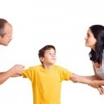 Hands of parents fighting over their son each pulling him their way.