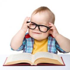 A baby wearing glasses pretending to read