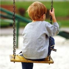 A boy sits on a swing, alone and sad.
