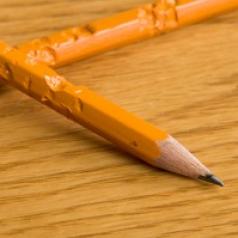 Two chewed up pencils sit on a table.
