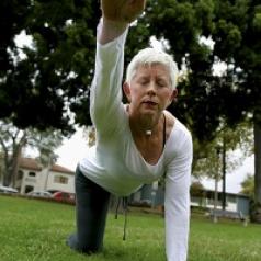 An older woman does yoga on a lawn.
