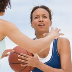 A woman looks for an opportunity to pass a basketball.