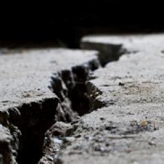 A close-up picture of a large crack in concrete pavement.