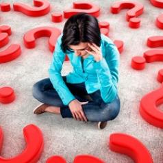 Woman sitting surrounded by question marks