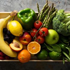 Overhead view of fresh and colorful vegetables and fruits in a wooden crate