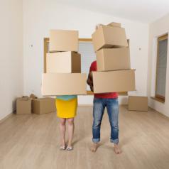 Moving couple holds stacks of boxes