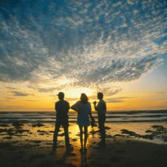 Three friends watch a sunset on the beach