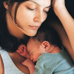 Exhausted mother sleeping with newborn