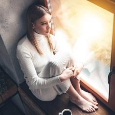 Serious woman sits in window looking out