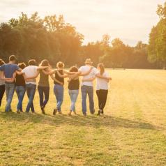 Rear view of ten people in a field with linked hands