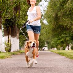 Action shot of young woman happily jogging with dog