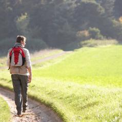 Young man walks along path through grassy hill