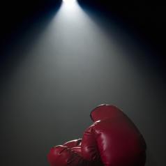 Red boxing gloves under spotlight