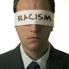 Blindfolded man with "racism" text on the blindfold