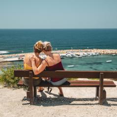 Female couple on bench admiring the sea