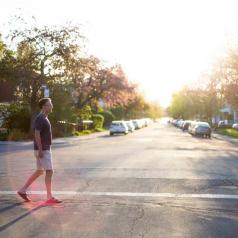 Man walking across street in a quiet neighborhood at sunset
