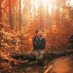 Man sitting on log in autumn forest with thoughtful expression