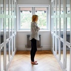 Woman standing in dressing room with mirrors on each of the locker doors