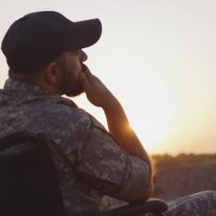 Military veteran sitting in wheelchair, thoughtfully watching a sunset