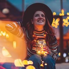 Smiling woman holding glowing string lights