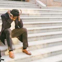 Distressed man sitting on outdoor steps after losing job