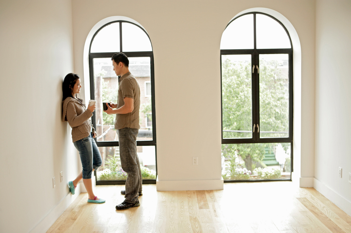 Standing couple has conversation by large arched window