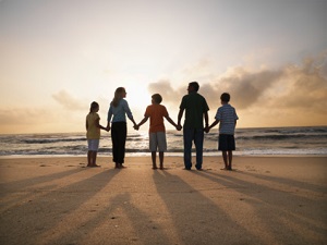 Family standing hand-in-hand on the beach