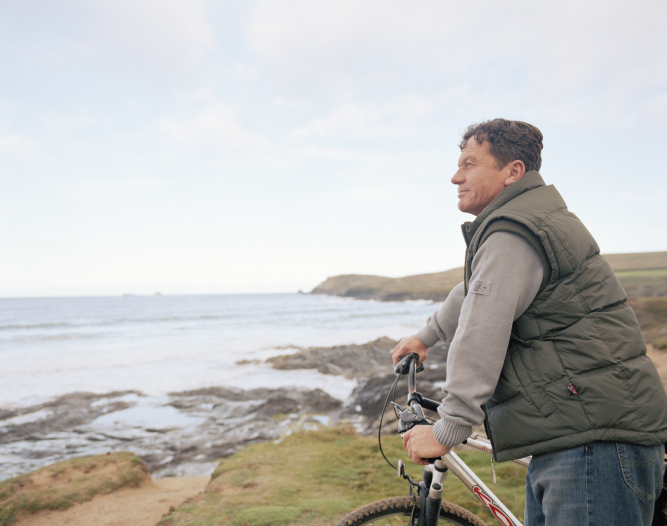 Man on coast holds bike handlebars