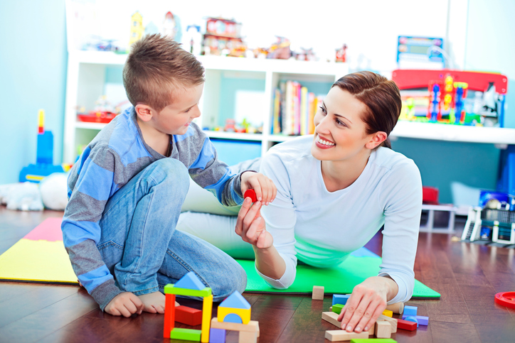 Mother and son play together on floor of playroom
