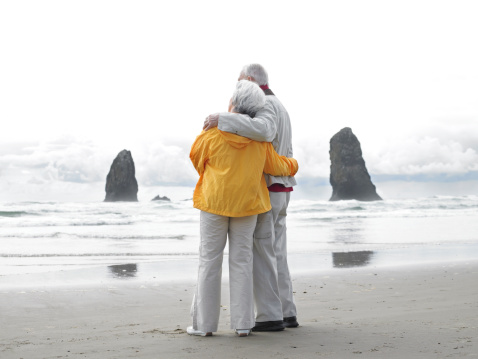 A senior couple embraces on the beach
