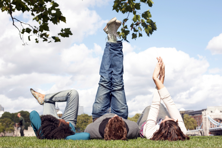 Three friends lying under a tree, legs in the air