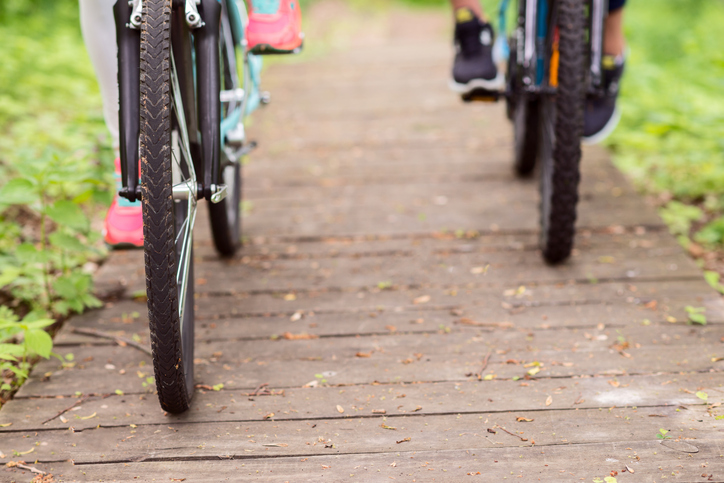 View of the legs and bike tires of two bicyclists riding on path