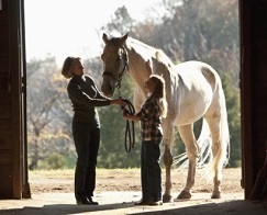 Woman and girl standing with white horse