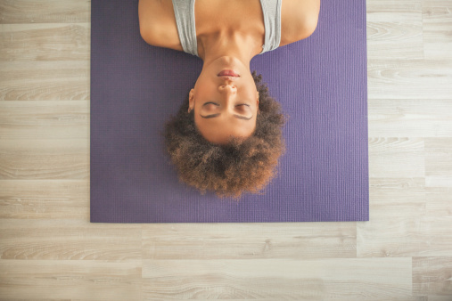 Woman lying on mat with eyes closed