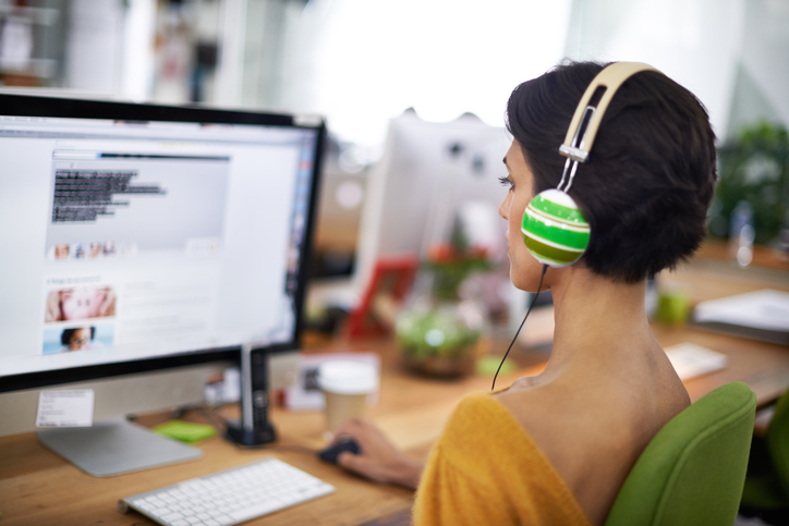 Rear view photo of person working at office desk wearing headphones