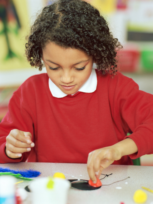 A young girl makes a collage with paint and other tools