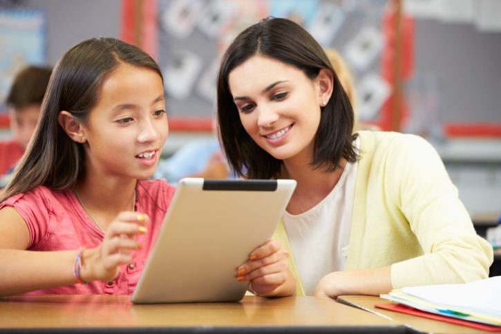 A young girl using a tablet and working with a tutor