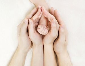 Close up of mother and father cradling baby's hand