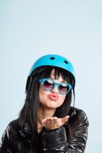 Woman wearing bike helmet and sunglasses blows a kiss