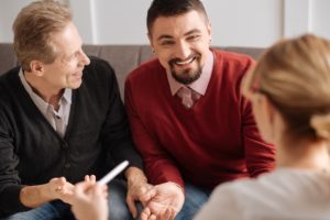 LGBT couple sits on couch across form therapist, in conversation