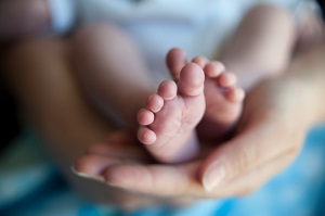 A pair of baby's feet rest on a woman's hand. 