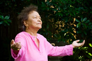 older woman opening her arms to nature