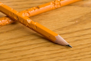 Two chewed up pencils sit on a table.