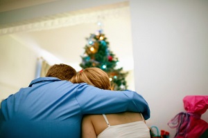 A couple embraces beneath a Christmas tree.