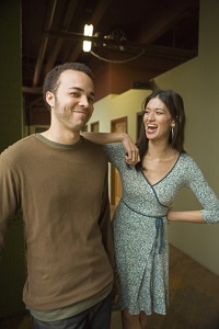 A multicultural couple smiles, playfully, at each other.