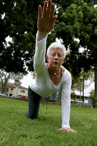 An older woman does yoga on a lawn.